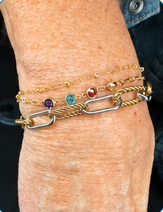 A stack of gold and silver bracelets with colorful charms