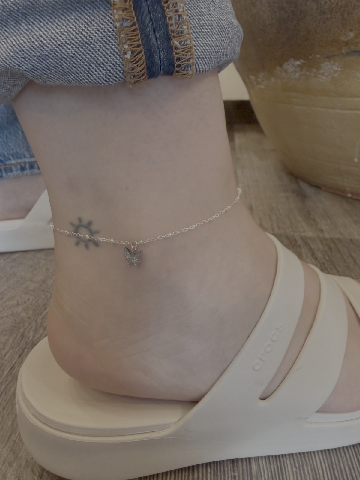 A fine chain anklet featuring a small sun charm