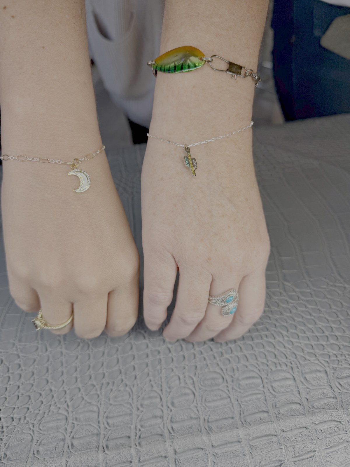 Two wrists with personalized chain bracelets and charms