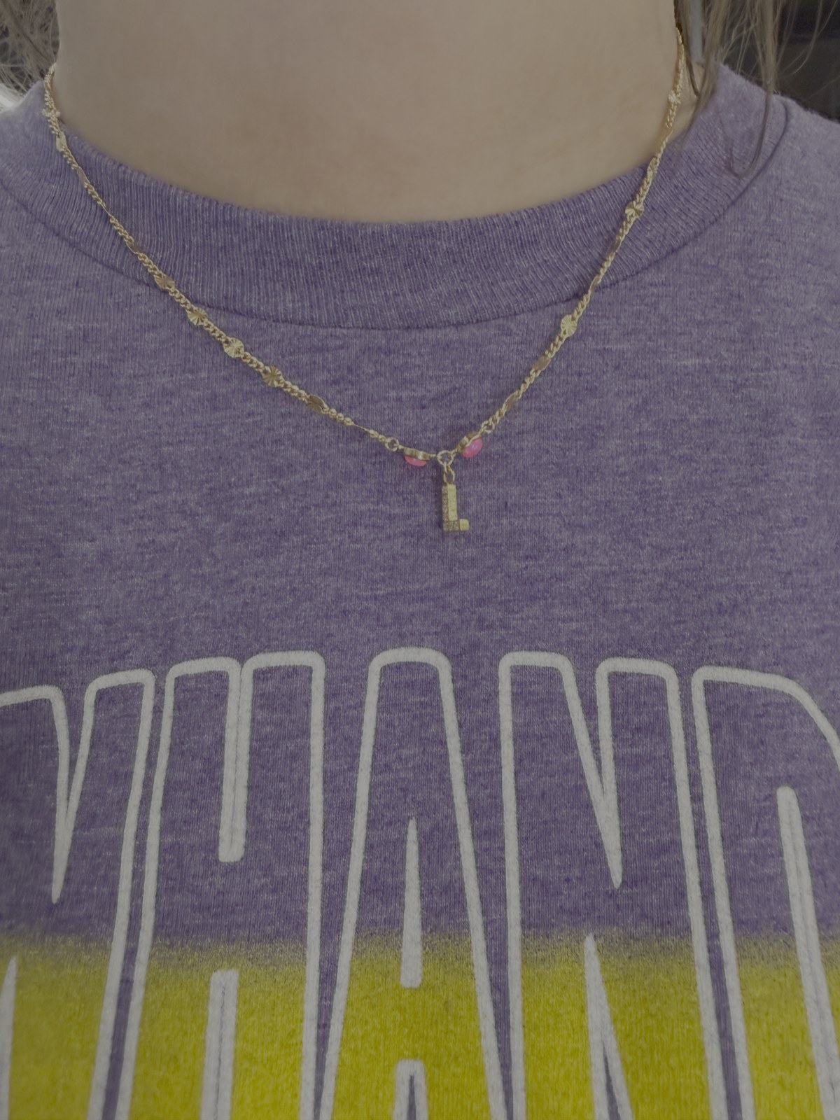 Gold chain necklace with a letter charm and colorful accents