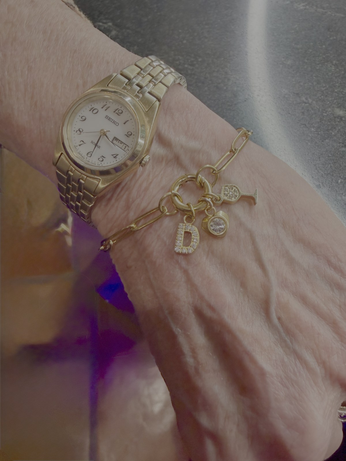 A gold link bracelet with a letter and multiple personal charms