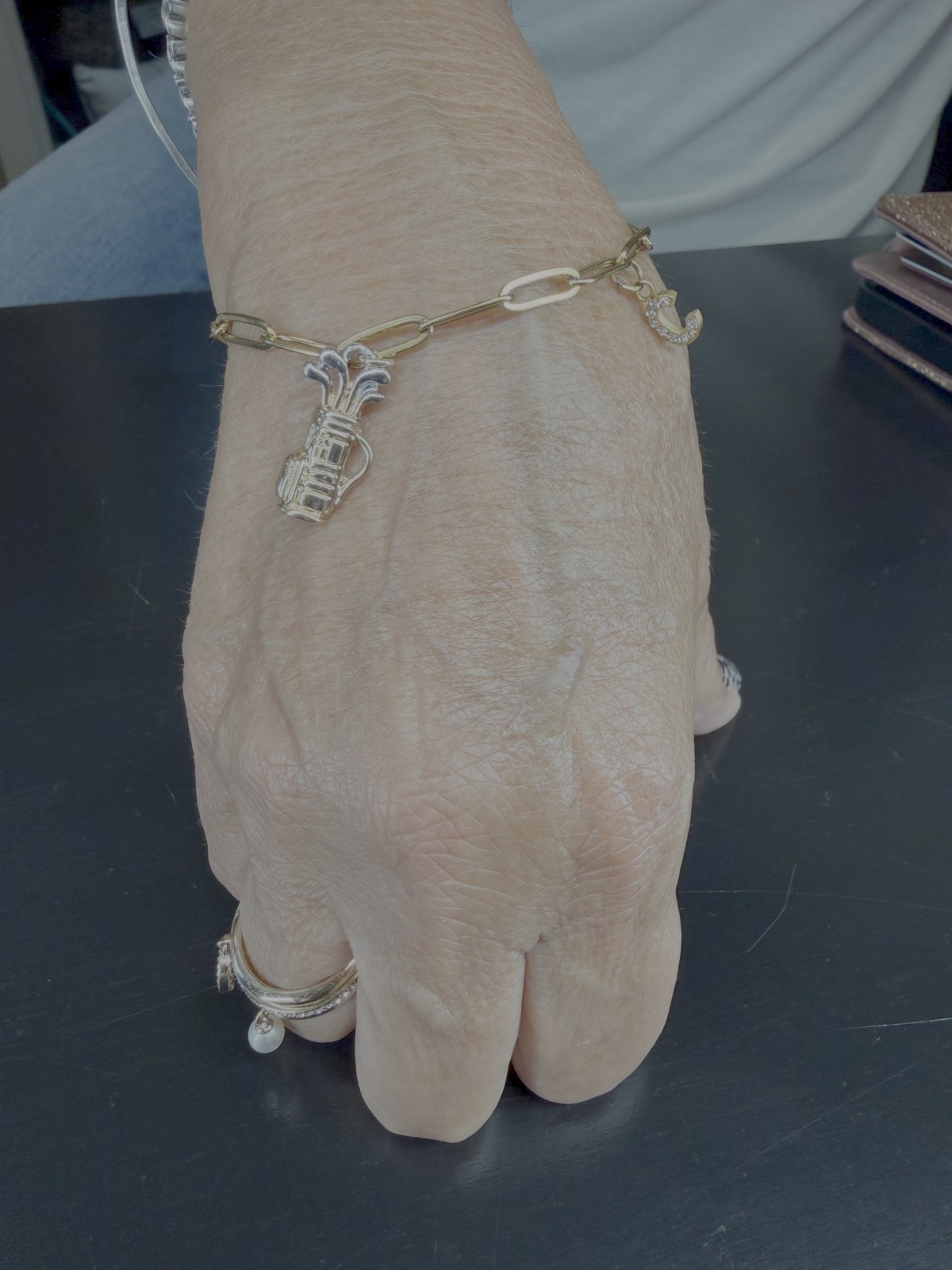 A removable gold link bracelet with a dangling charm