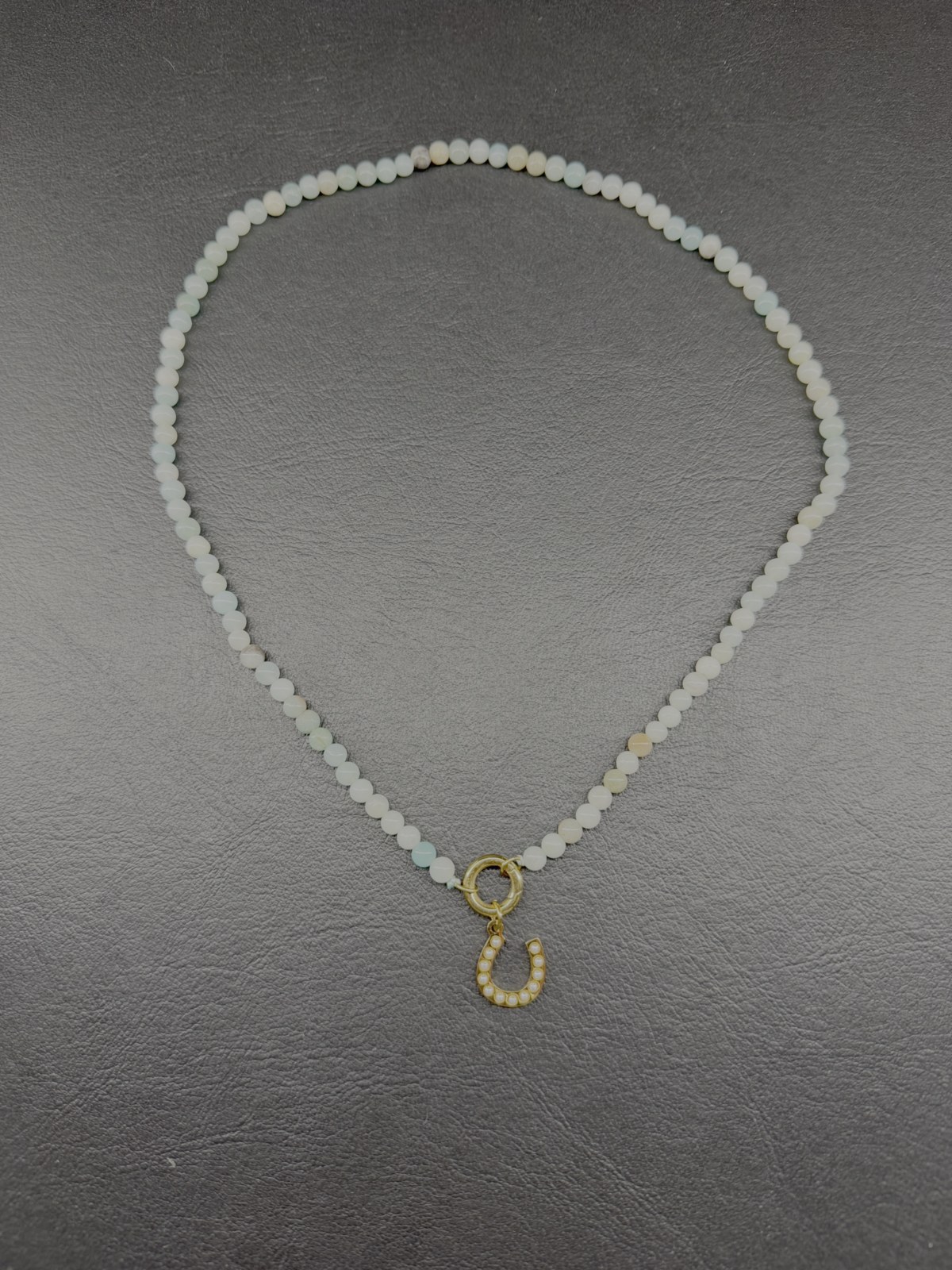 White beaded necklace with a gold horseshoe charm
