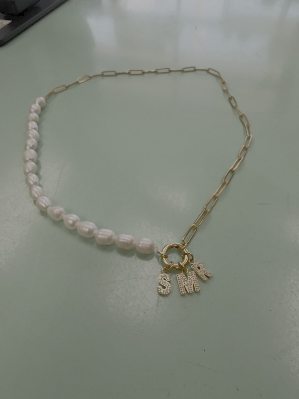 Necklace combining white beads and a gold link chain with charms