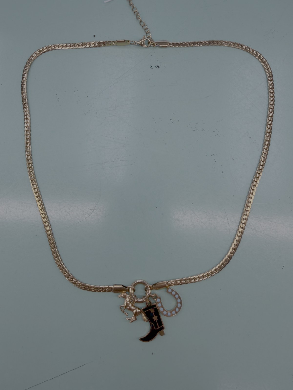 Gold chain necklace with a boot and small charms
