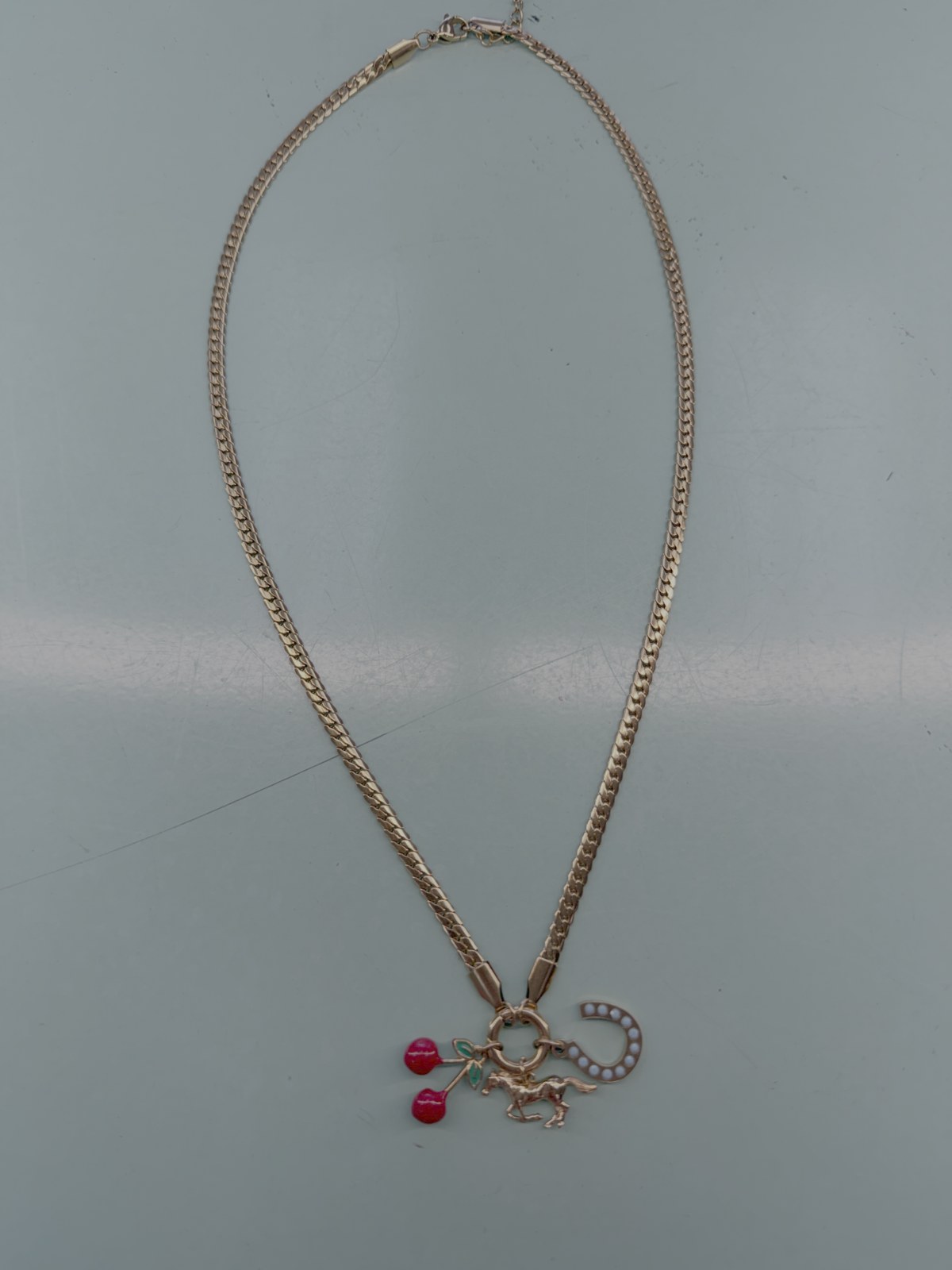Gold chain necklace with red accents and a horseshoe charm