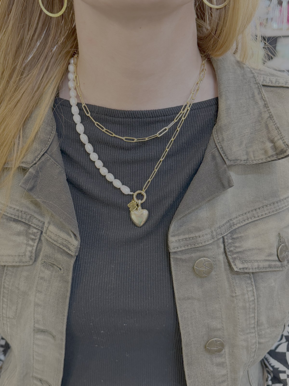 Layered gold chain and white beaded necklaces worn together